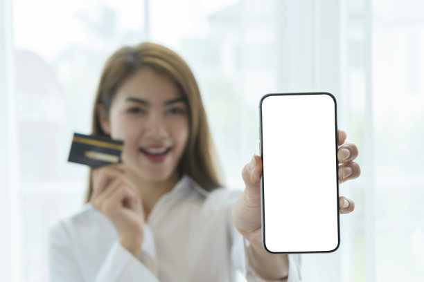美丽的亚洲女孩谁在网上购物使用数字智能手机信用卡网上购物。一个空白，白屏输入广告文本。图片下载