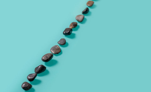 类似鹅卵石的小石头斜放在绿松石的背景上。图片下载