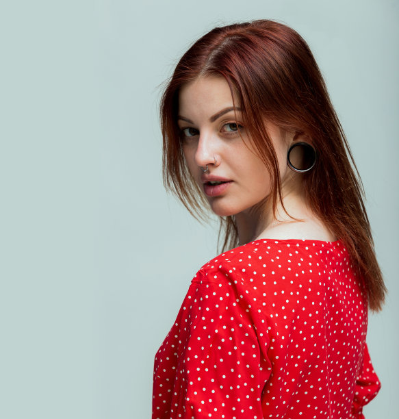 脸上的表情。微笑的女人，耳朵上有个隧道，鼻子穿了洞。灰色背景，拷贝空间。女人的脸为文字刺穿空间图片下载