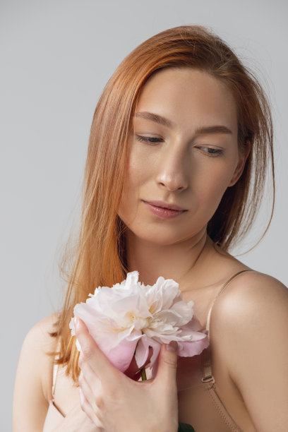 美丽的红发女人的肖像在内衣与花孤立在灰色的工作室背景。健身、饮食、运动、自然美和美容理念。图片下载