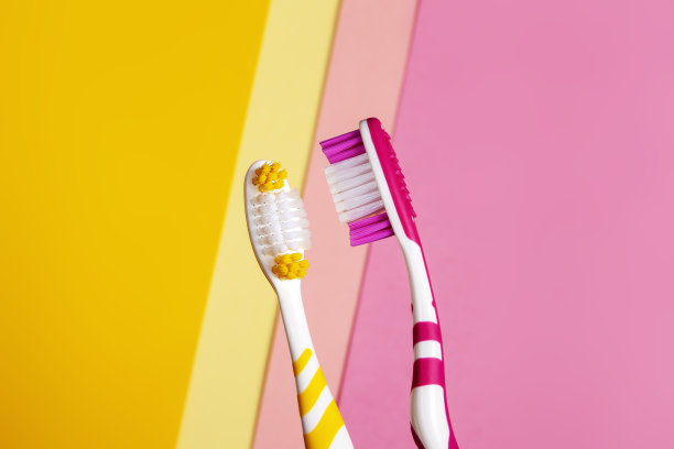 两种颜色的牙刷，黄色和粉色。2颜色背景。图片下载