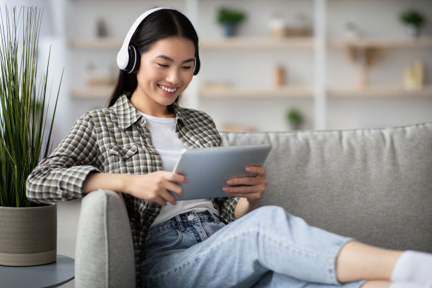 漂亮的亚洲女士看电影，使用耳机和垫图片下载