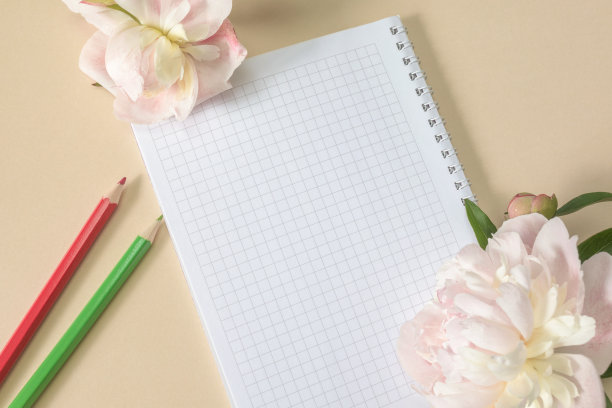 春天的笔记本和彩色铅笔，米黄色的大花和牡丹芽在米黄色的背景。前视图。本空间图片下载