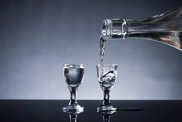 烈酒或烈性酒是从一个瓶子的背景倒进玻璃杯图片下载