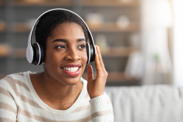 微笑的年轻黑人女士在无线耳机听音乐的特写镜头图片下载