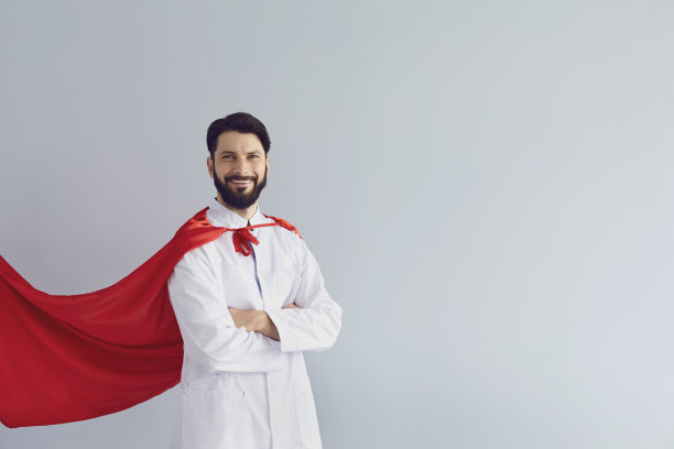 博士是个超级英雄。身穿超级英雄服装的医生在灰色背景下微笑。图片下载