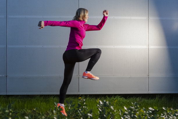 在金属墙的背景下进行户外慢跑训练的成熟女运动员。水平图像组成图片下载