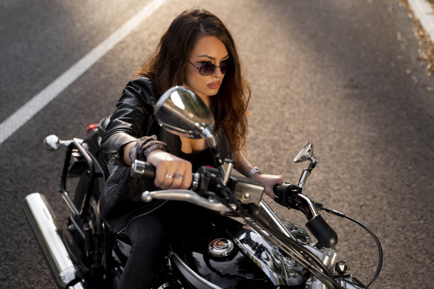 迷人的女孩戴着太阳镜在日落的道路上骑自行车图片下载