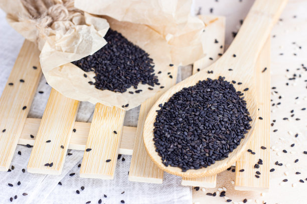 黑芝麻放在木勺里，在厨房的灯光背景下烹饪图片下载