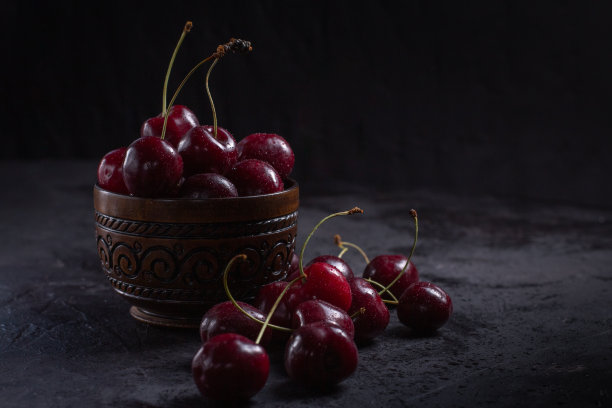 有机多汁的樱桃在一个碗里，水滴在浆果上在黑色的背景。特写照片，低调。图片下载