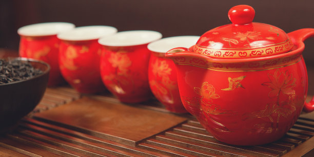 中国茶道。陶土制成的陶瓷茶壶和木制背景的碗。图片下载