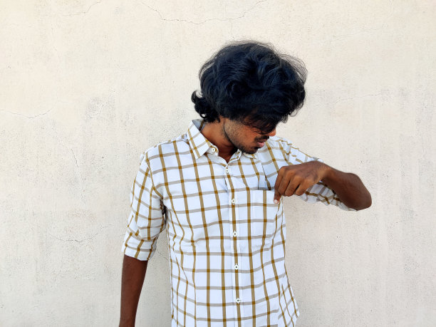 一个留着长发的年轻人用左手检查他的衬衣口袋。没有钱或拿钱图片下载