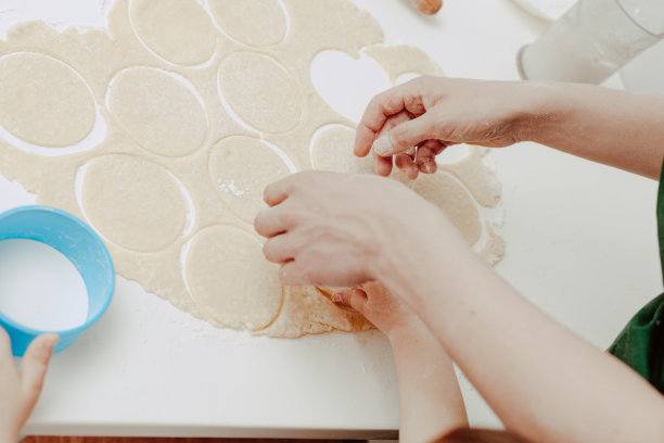 幸福的家庭在厨房。爸爸和儿子准备面团，烤饼干。休闲的生活方式，漂亮的孩子，节日概念，擀面杖，曲奇切割机和面团。图片下载