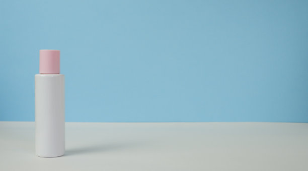 白色的桌子上，有一个粉红色的盖子，蓝色的背景。右边留有文字空间。左边为文本留出空间。时尚的产品外观，布局，身份。图片下载