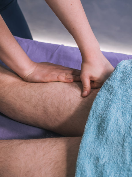 两个人，理疗师按摩着男人的腿部肌肉——腿筋。图片下载