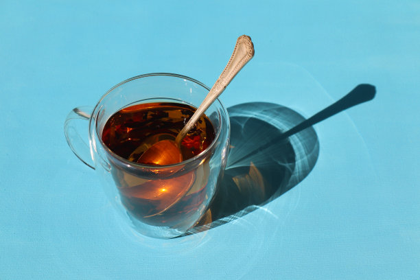 蓝色背景上放着勺子的茶杯图片下载