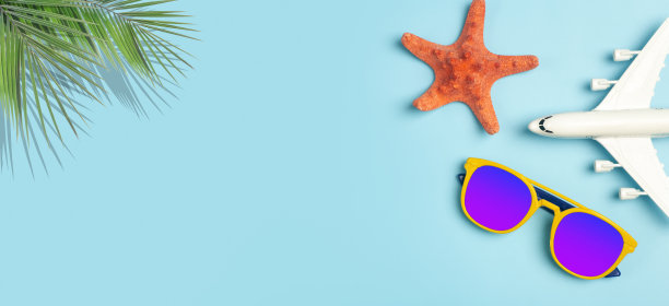 夏天旅游的背景。太阳镜，热带棕榈叶，飞机和海滩配件在彩色的蓝色背景。旅游度假、休闲度假、避暑理念。图片下载