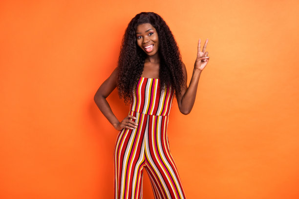 照片的快乐的非洲裔美国年轻女子手拉手腰做v标志孤立在橙色的背景图片下载