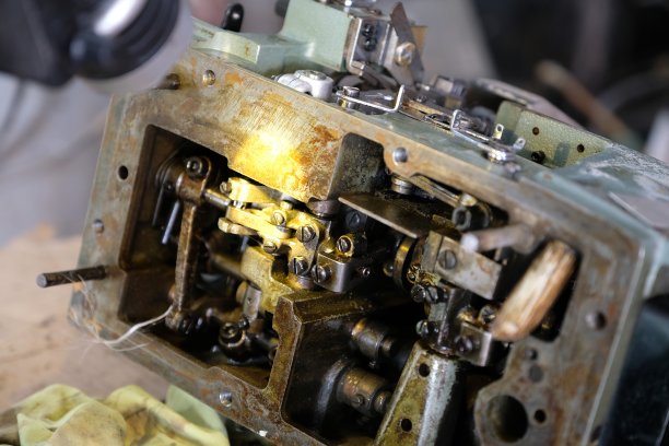 技工打开缝纫机内部进行维修。图片下载