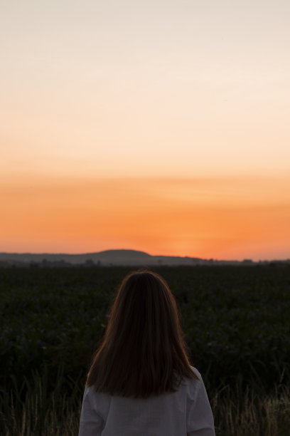 日落时分，年轻女子在田野里。图片下载