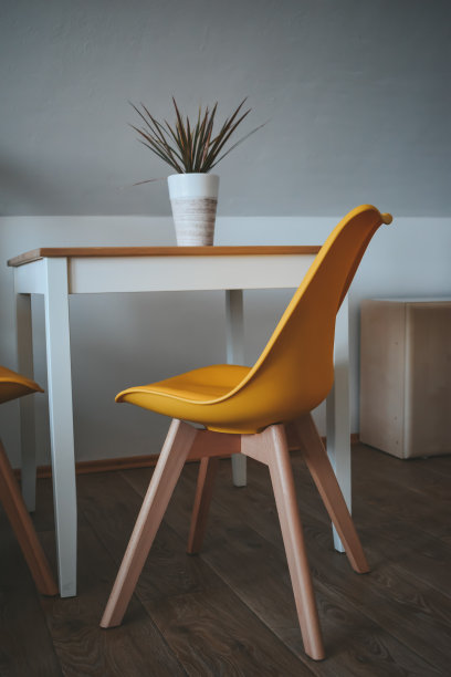 明亮的黄色餐椅和带有植物的木桌，后面是白色的墙壁图片下载