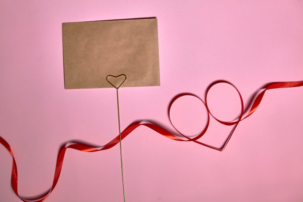 心形红色丝带在粉红色的背景，俯视图。节日装饰。心形的丝带。情人节贺卡图片下载