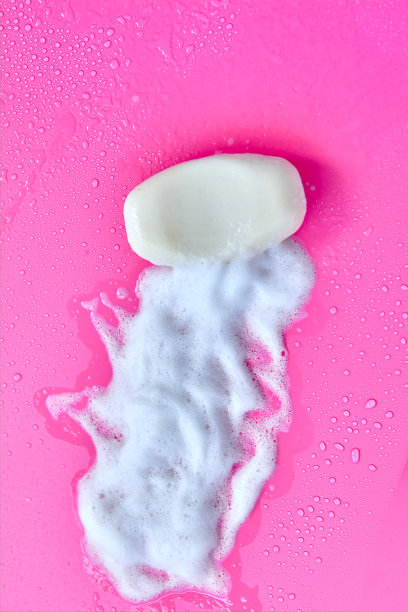 清洗的概念。粉红色背景上的泡沫和肥皂。清洁服务图片下载