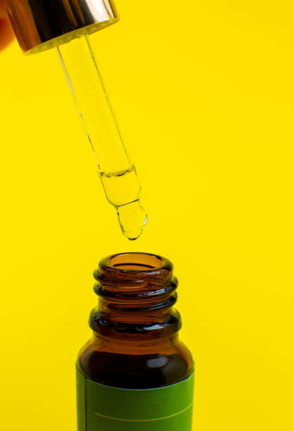 黄色背景上带吸管的化妆油。闭上液滴滴落。美容、医药、保健理念。宏观照片。自然,生态化妆品。图片下载
