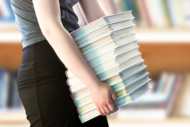 回到学校，努力学习。在图书馆里抱着一大堆书的女孩图片下载