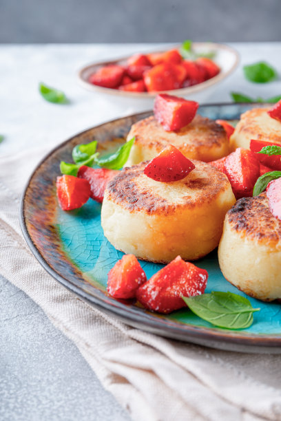 白软干酪煎饼与草莓和薄荷在一个蓝色盘子近距离垂直照片图片下载