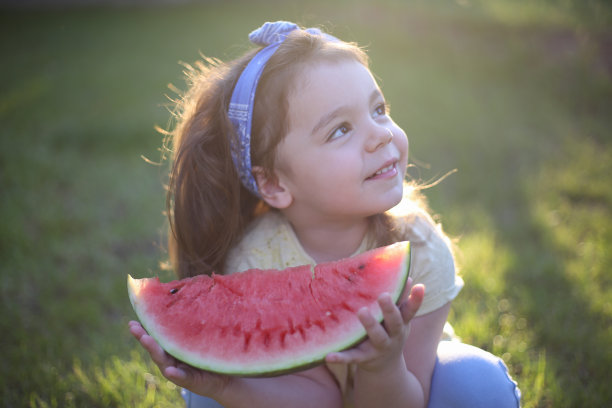 可爱的小女孩在吃新鲜的西瓜水果在花园库存照片图片下载