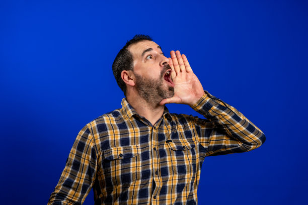 年轻的拉丁商人穿着优雅的衬衫和领带站在孤立的蓝色背景大喊大叫，大声尖叫，用手捂着嘴。图片下载