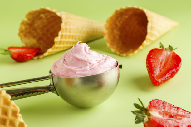冷夏天然甜品。绿色背景下的草莓蛋筒和勺子冰淇淋。新鲜的草莓。图片下载