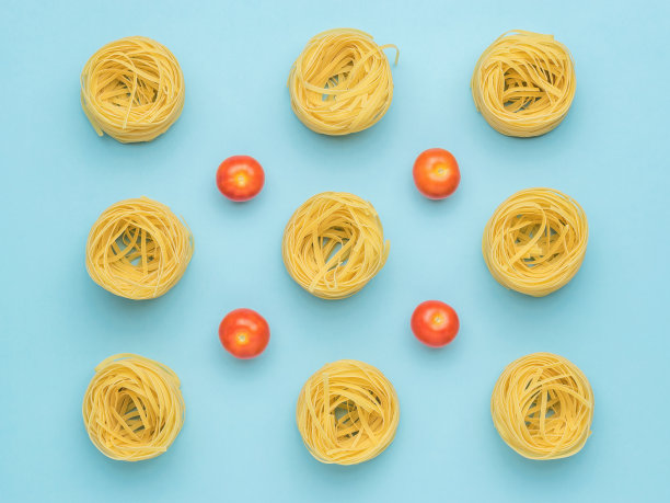 蓝色背景上的意大利面和新鲜的西红柿。图片下载