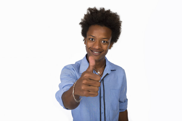 年轻的黑人男子与非洲发式穿蓝色衬衫在孤立的白色背景做快乐的拇指向上的手势与手。图片下载
