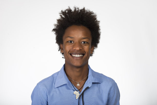 年轻的黑人男孩看着照相机，在白色的背景下微笑。图片下载