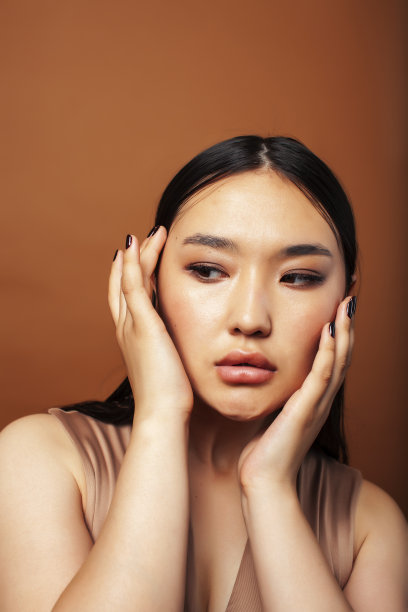 年轻漂亮的亚洲女人愉快的微笑在温暖的棕色背景，生活方式的人的概念图片下载