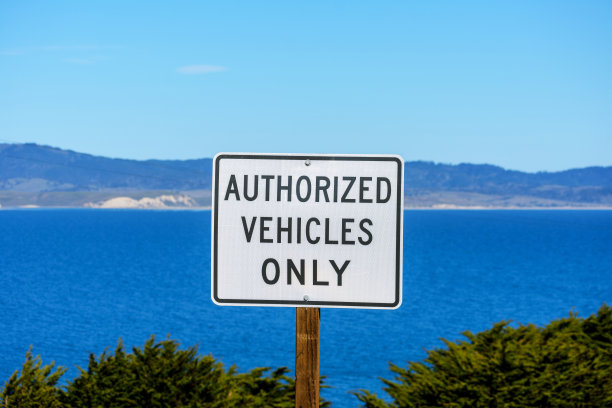 只有授权车辆通行的道路标志。从远处可以看到海湾和海岸线的平静水面图片下载