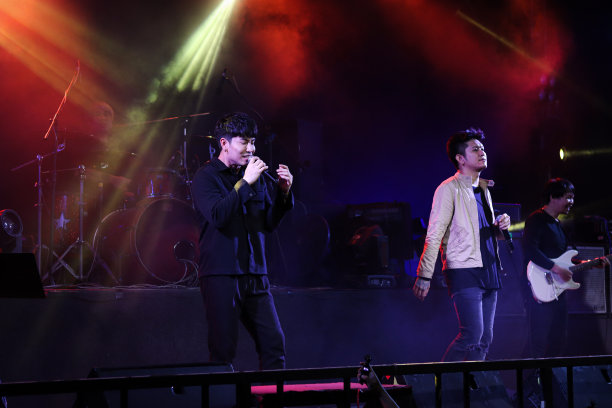 歌手和音乐家在音乐节的摇滚舞台音乐会上展示，彩色的光芒明亮的聚光灯，散景和烟雾在黑暗的背景。图片下载