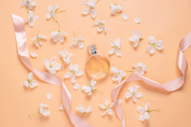 香水瓶和精致的花白色花瓣在柔和的粉红色背景平布局图片下载