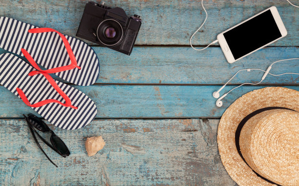 在沙滩上放松的不同物品的静物，橡胶人字拖，帽子，照相机，手机，太阳镜，耳机在木制的蓝色背景。一个青年之旅的概念，在海滩上休息，带着香水图片下载