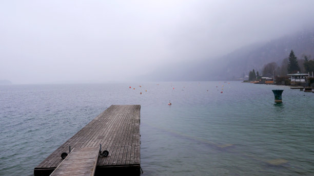 奥地利圣吉尔根的初春，沃尔夫冈湖，木栈桥和笼罩在薄雾中的山丘图片下载