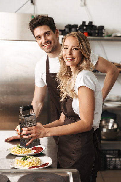 年轻快乐的朋友，恩爱的情侣厨师在厨房做饭。图片下载