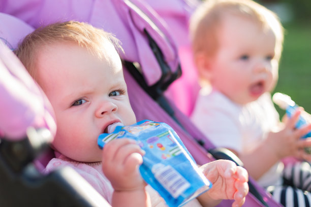 饥饿的双胞胎女孩手拿土豆泥在街上的肖像图片下载