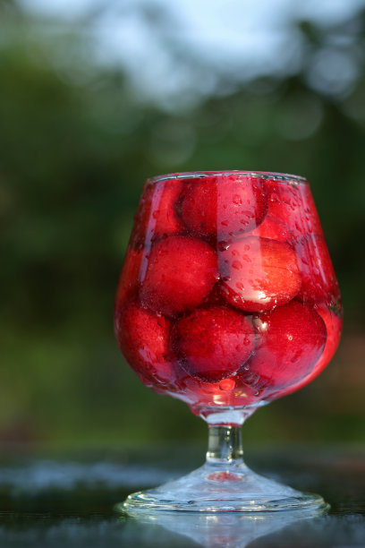 杯子里的樱桃。浆果酒精饮料概念。红酒。樱桃微距细节特写。春天的浆果。季节性的浆果。模糊背景上的樱桃酒或烈酒。自制的红樱桃酊图片下载