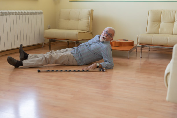 一名拄着拐杖的残疾退休人员跌倒在客厅的地板上。图片下载