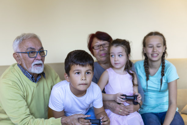 微笑的孩子坐在客厅的沙发上，与大家庭一起享受时光，同时玩主机游戏。图片下载