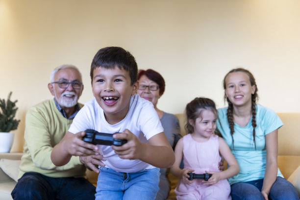 高兴的弟弟和妹妹在家里用操纵杆玩电子游戏。图片下载