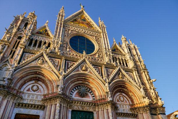 夕阳的光芒照亮了锡耶纳中心的大教堂令人惊叹的哥特式立面图片下载