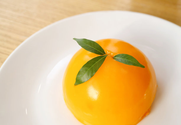 令人垂涎三尺的鲜亮橘色圆蛋糕放在白色盘子上图片下载